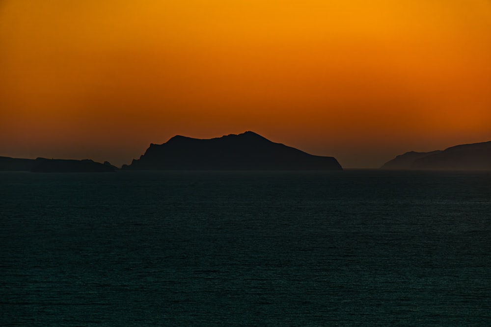 a sunset over a body of water with mountains in the distance