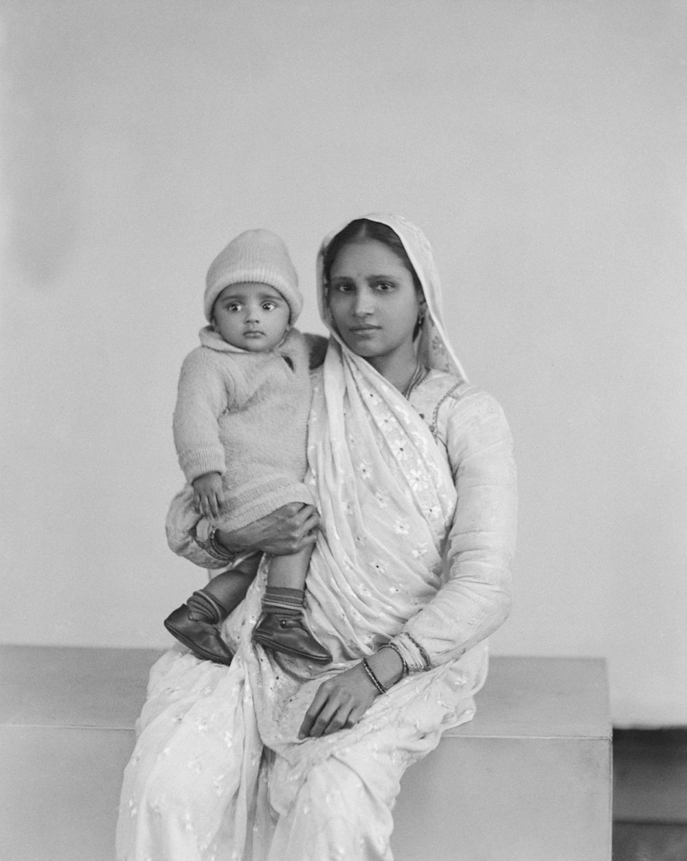 a black and white photo of a woman holding a baby