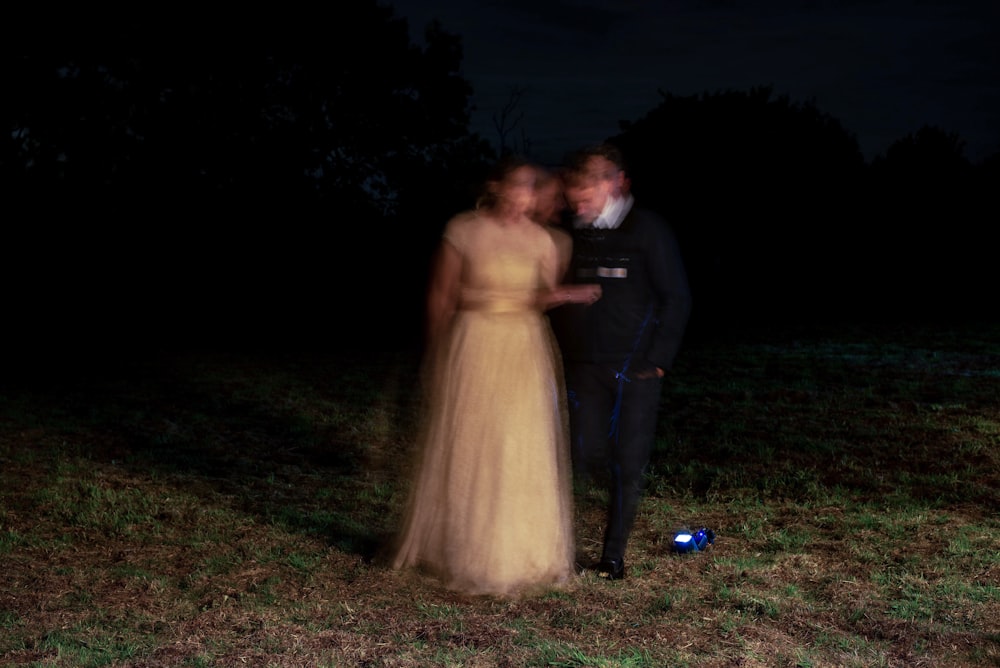 a man and a woman standing in a field at night