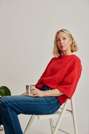 a woman sitting on a chair holding a cup of coffee