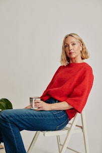 a woman sitting on a chair holding a cup of coffee