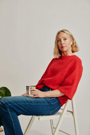 a woman sitting on a chair holding a cup of coffee