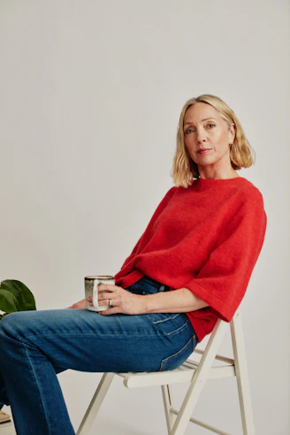 a woman sitting on a chair holding a cup of coffee