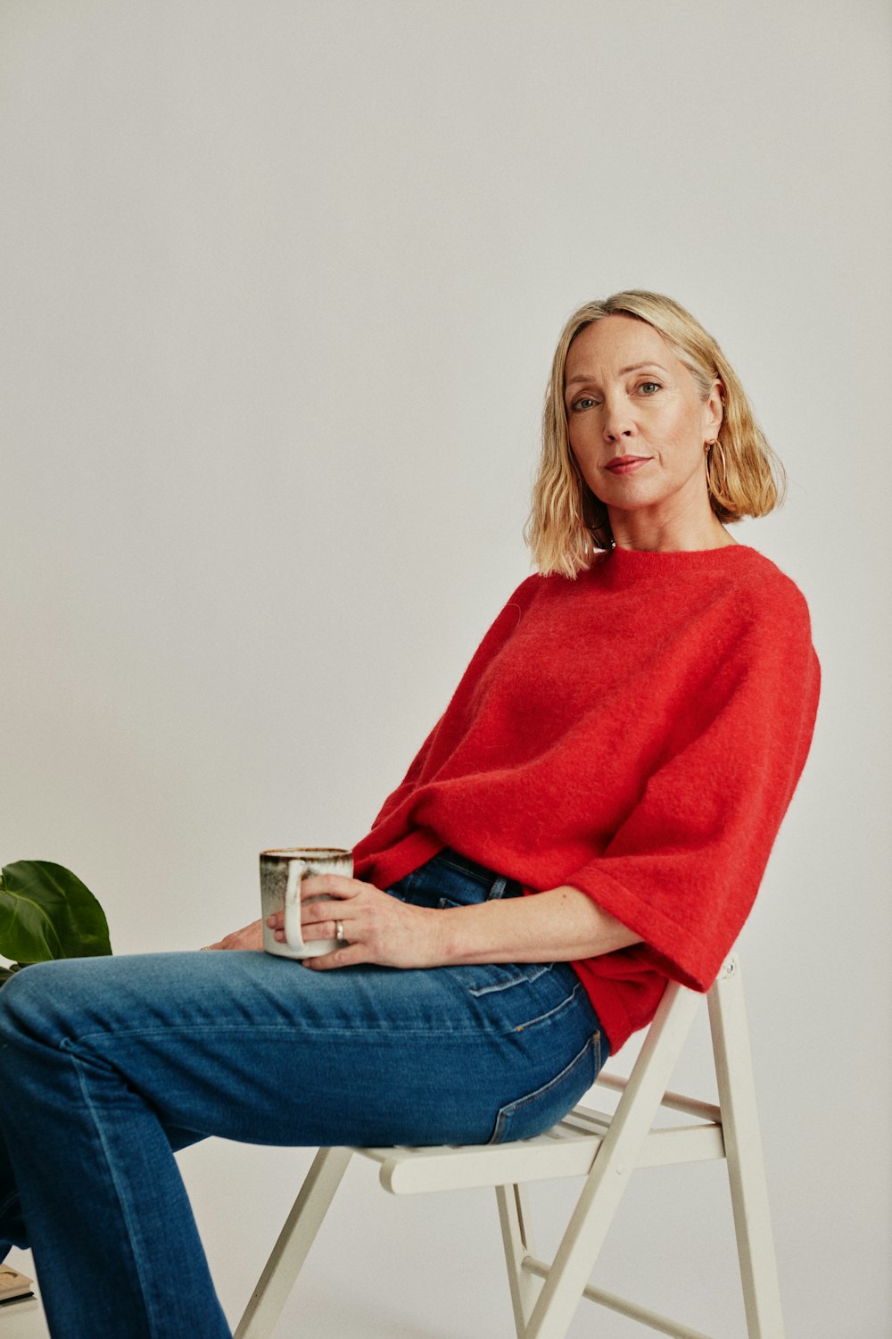 a woman sitting on a chair holding a cup of coffee