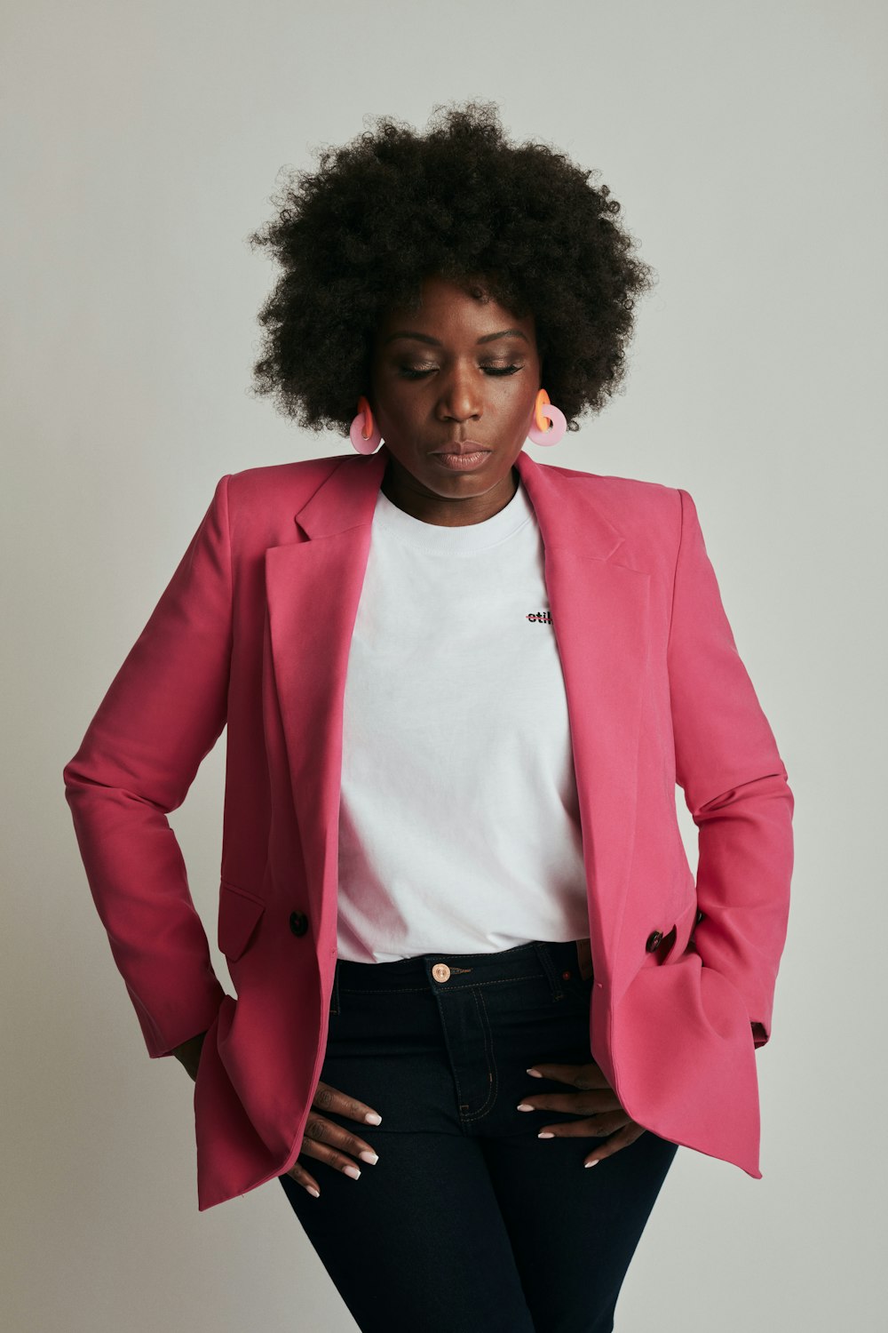 a woman wearing a pink jacket and jeans