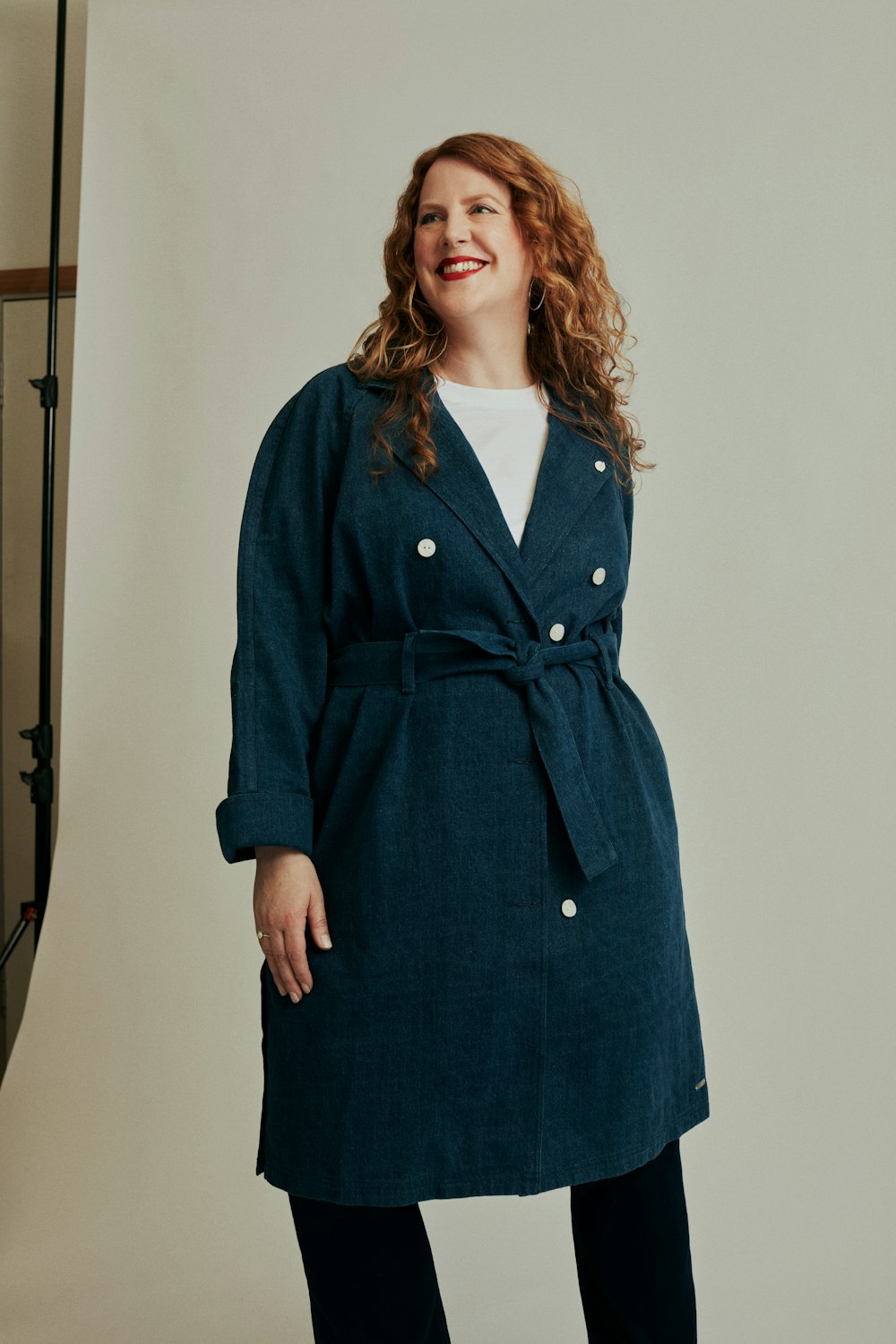 a woman standing in front of a mirror wearing a blue coat