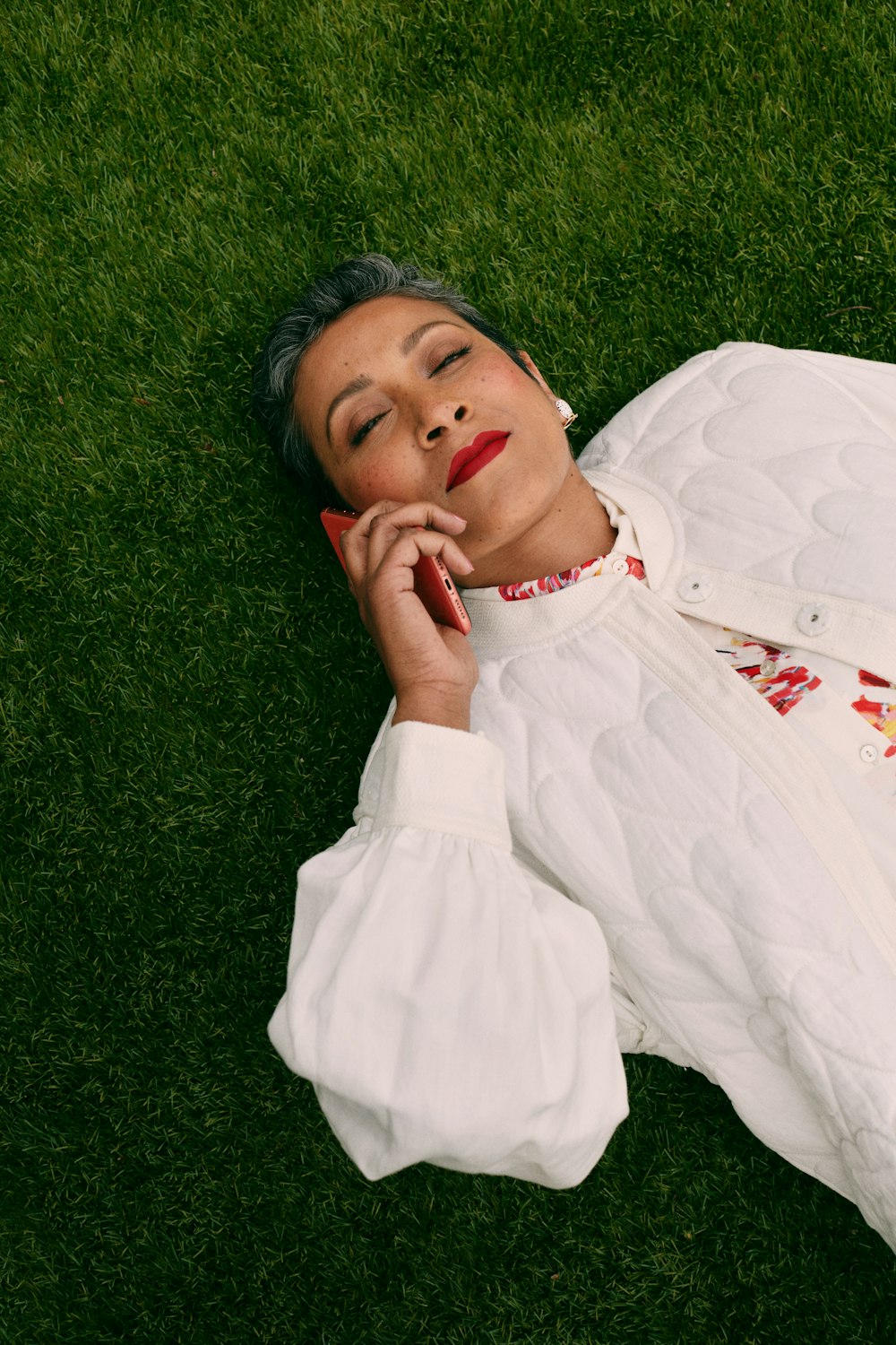 a woman laying on the grass with her eyes closed