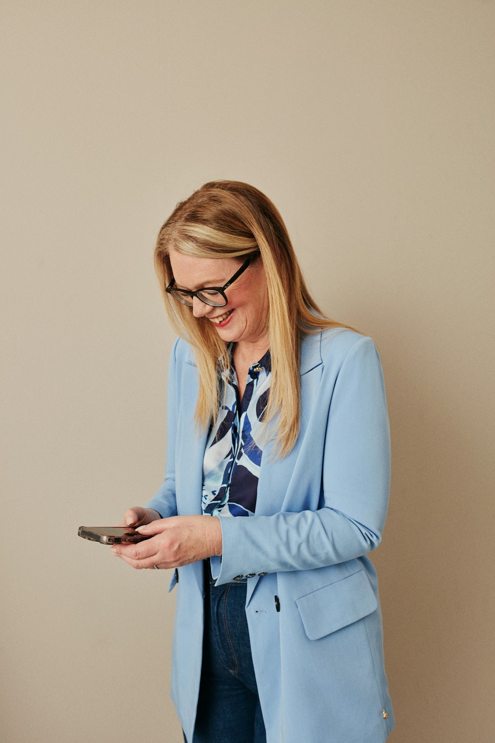 a woman in a blue jacket looking at her cell phone
