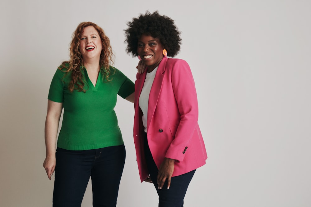 two women standing next to each other in front of a white wall