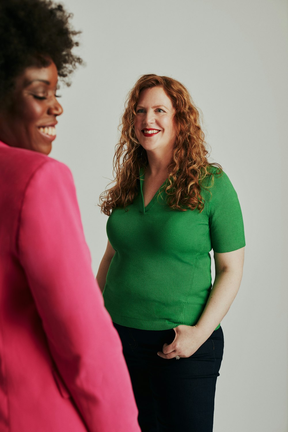 a woman standing next to another woman in a green shirt