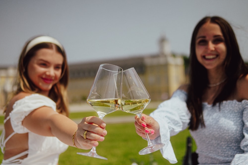 two women holding wine glasses in their hands