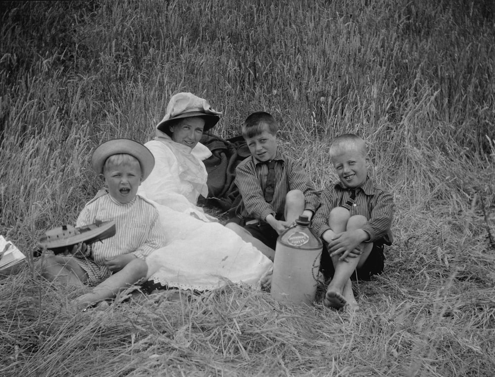 a black and white photo of a family sitting in a field