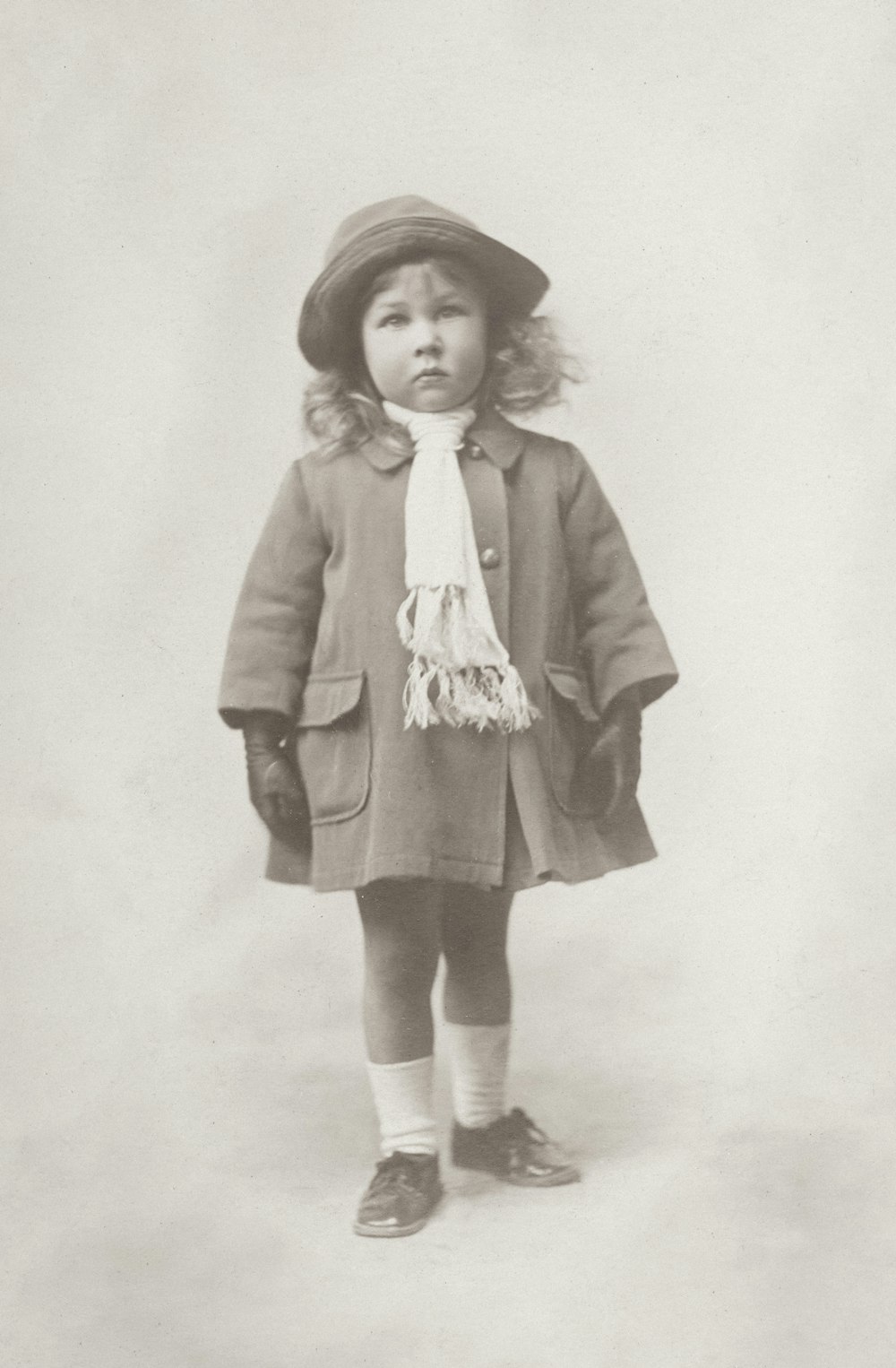 an old photo of a little girl wearing a hat and coat