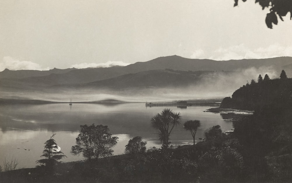 a black and white photo of a lake and mountains