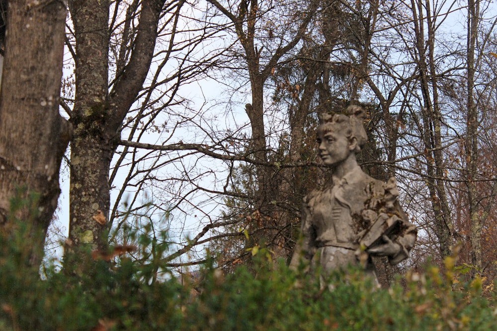 a statue of a woman in a wooded area