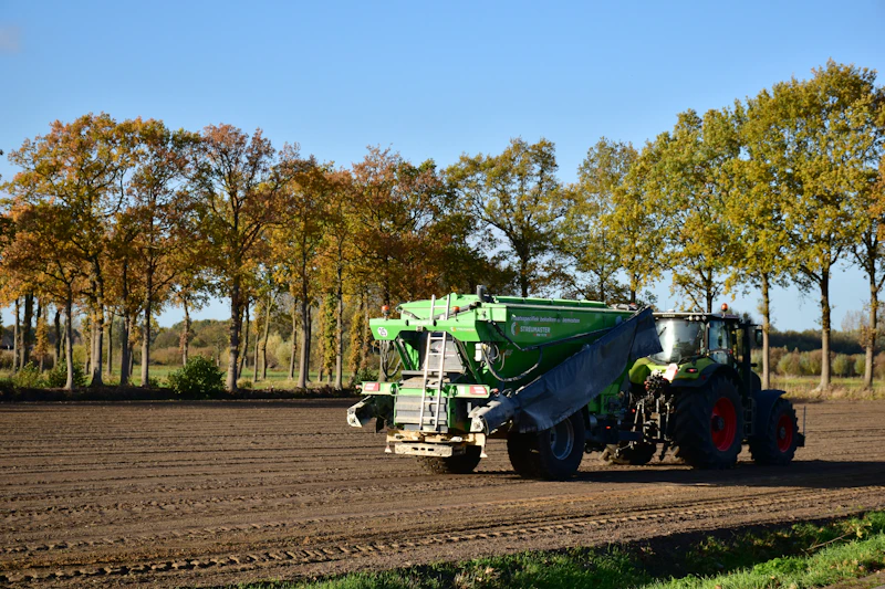 Tractor rijdt over zandpad langs veld
