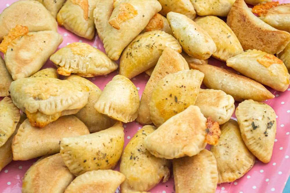 a pink plate topped with dumplings covered in cheese