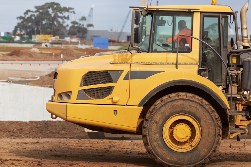 a large yellow truck driving down a dirt road