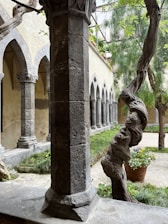 A serene cloistered abbey courtyard with stone arches and lush greenery.