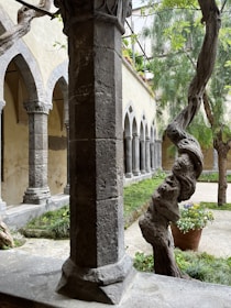 A quiet cloistered abbey courtyard framed by ancient stone arches and blooming greenery.