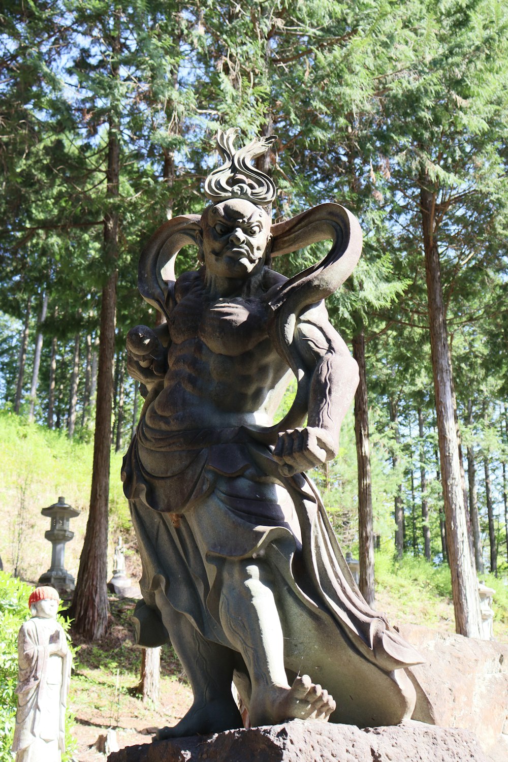 eine Statue eines Mannes, der einen Vogel in einem Wald hält