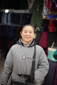 A smiling customer trying on a trendy jacket in front of a mirror inside the store.