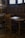 A small wooden desk and chair in a corner of a room with intricate wood paneling and two stained glass windows.