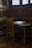 A small wooden desk and chair in a corner of a room with intricate wood paneling and two stained glass windows.