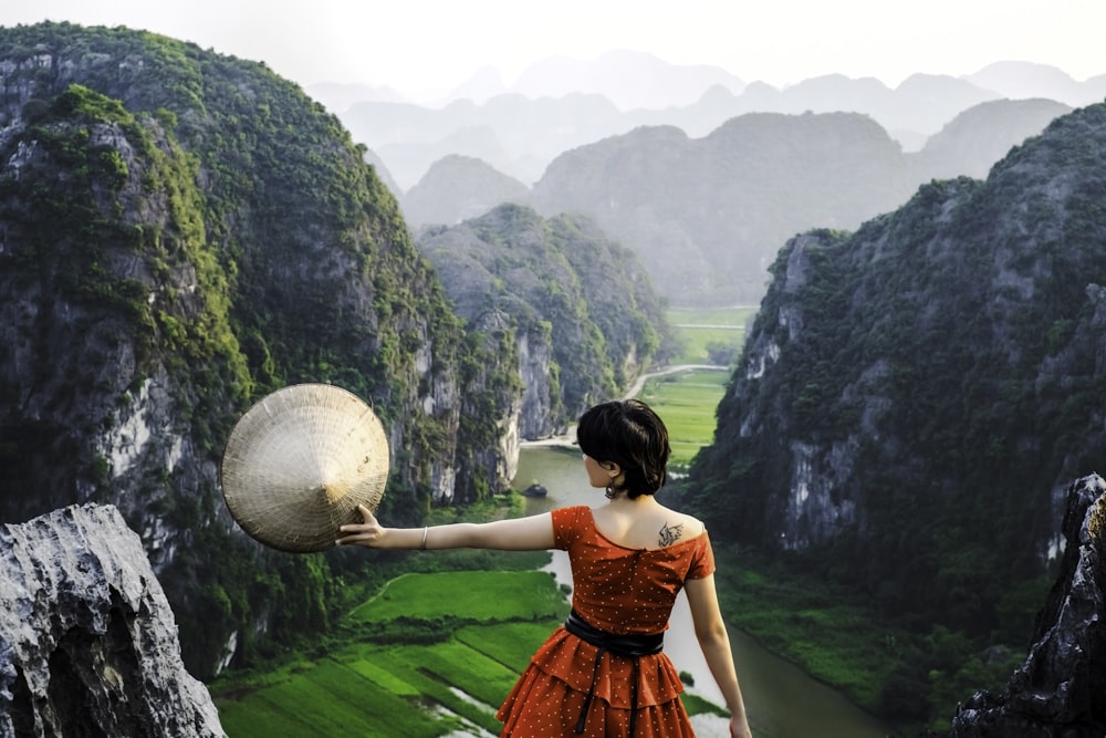 a woman in an orange dress holding a large rock