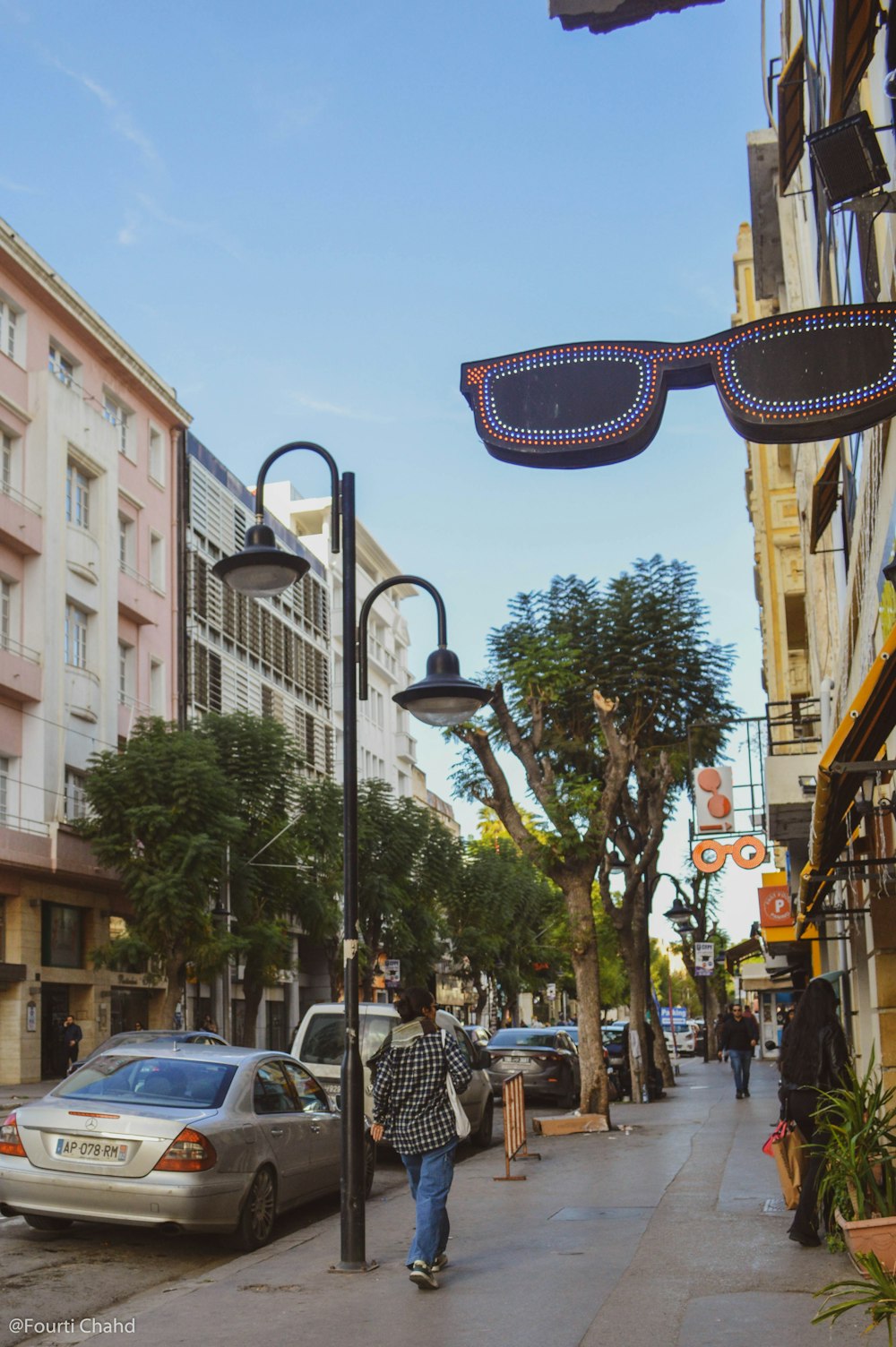 a man walking down a street next to tall buildings