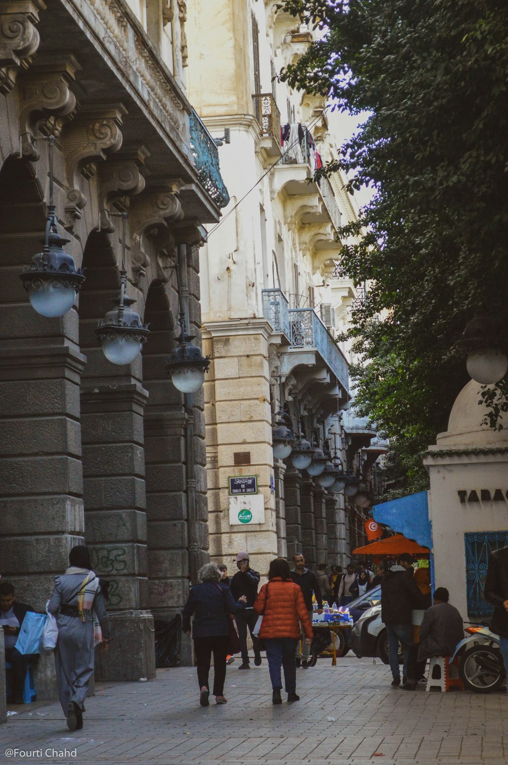 a group of people walking down a street next to tall buildings