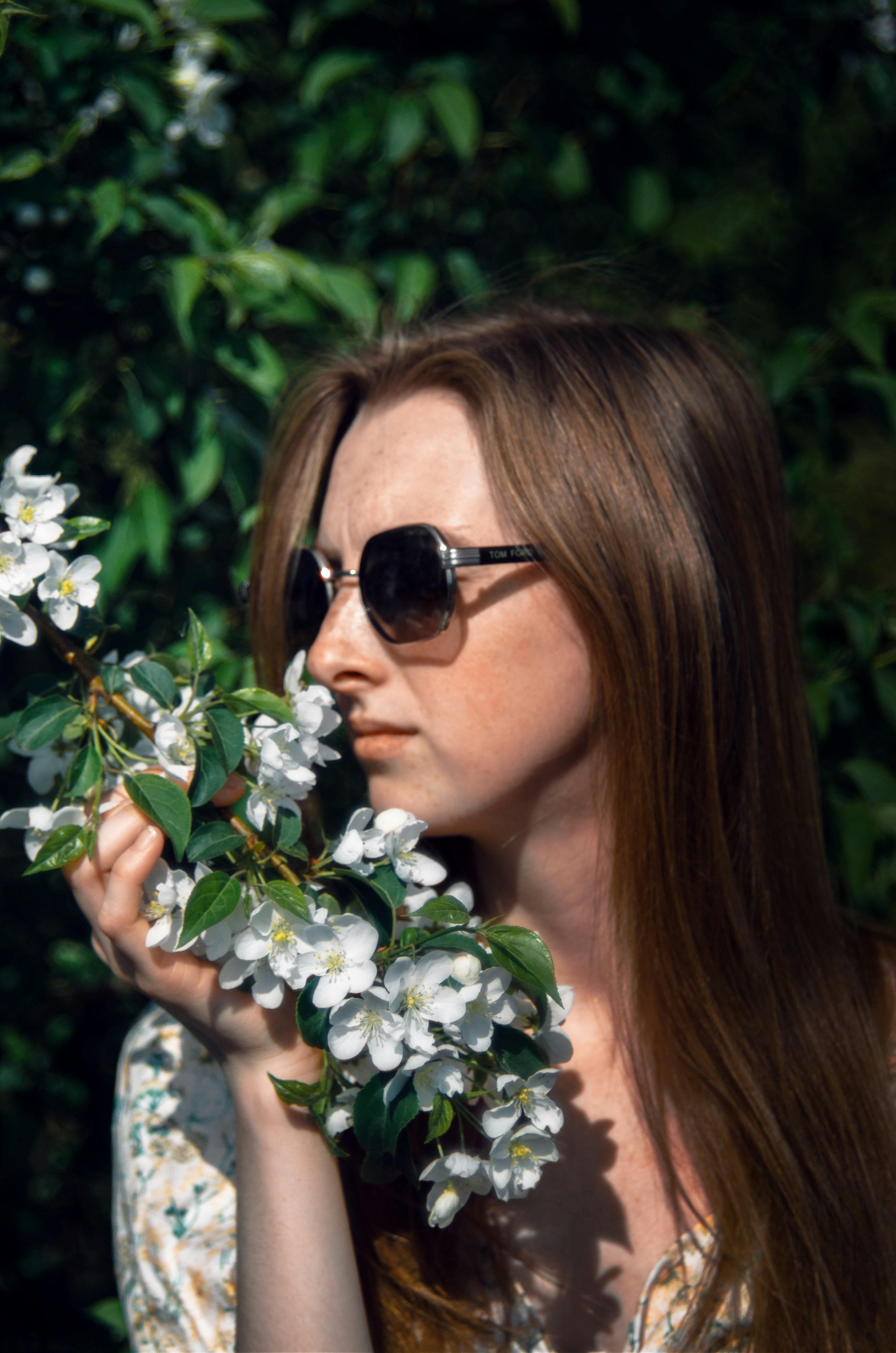 a woman wearing sunglasses holding a branch of flowers