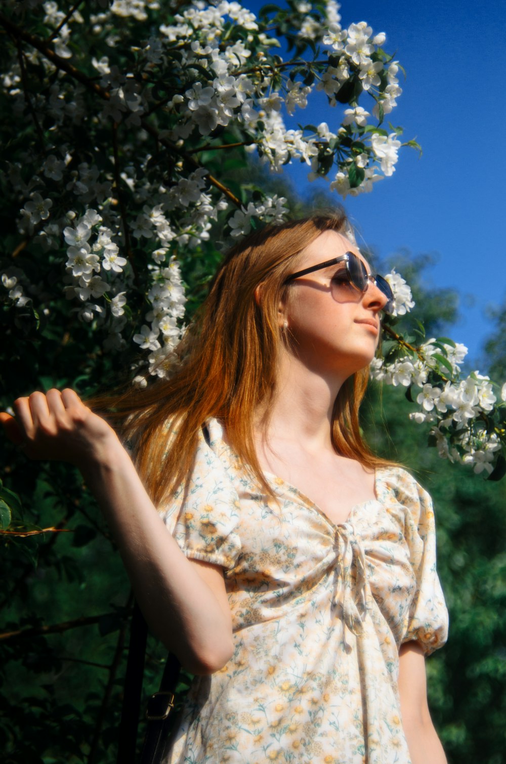 a woman in a dress standing in front of a tree