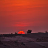 Sunset casting warm orange and golden hues over the vast dunes of Lençóis Maranhenses.
