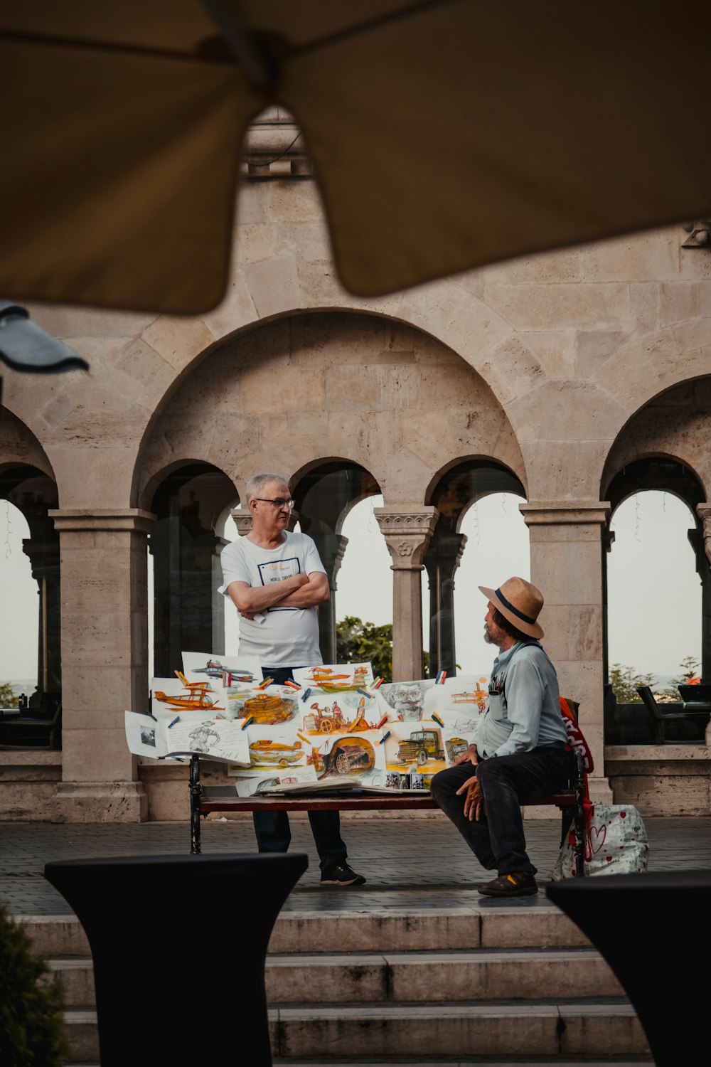 a man sitting on a bench next to another man