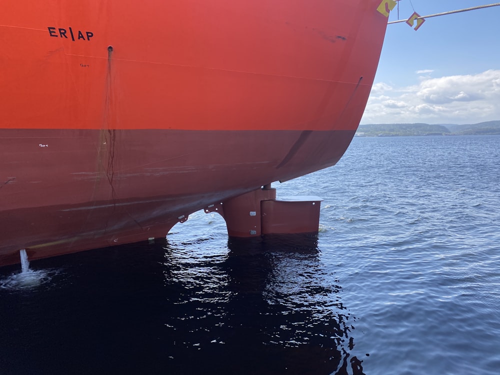 Un gran bote rojo sentado encima de un cuerpo de agua