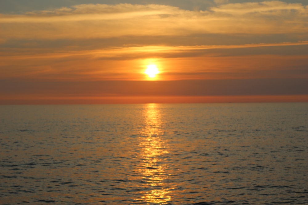 Il sole sta tramontando sull'oceano in una giornata nuvolosa