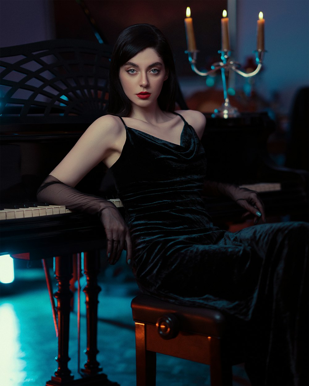 a woman in a black dress sitting at a piano