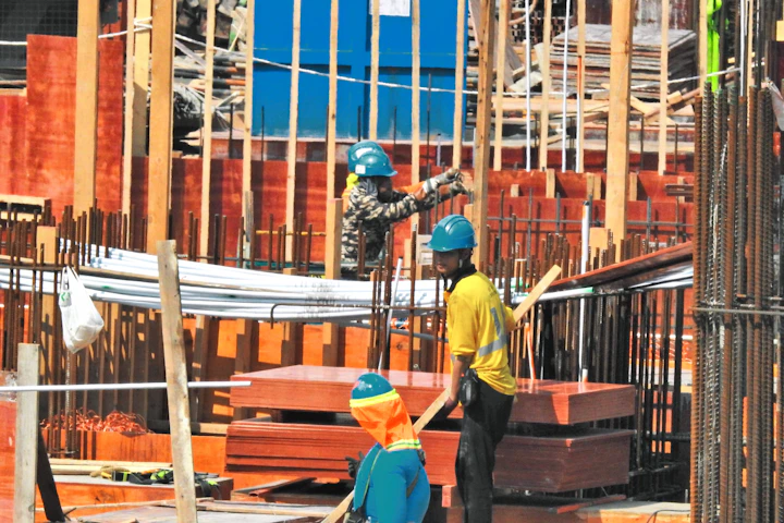 Workers performing building construction and finishing tasks on site.