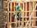 A construction worker wearing a blue hard hat and green safety vest works amidst bamboo scaffolding. The scene includes various construction materials such as wooden planks and metal reinforcements.