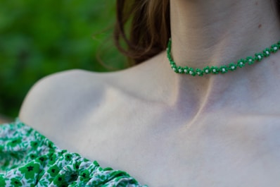 a close up of a woman wearing a green necklace