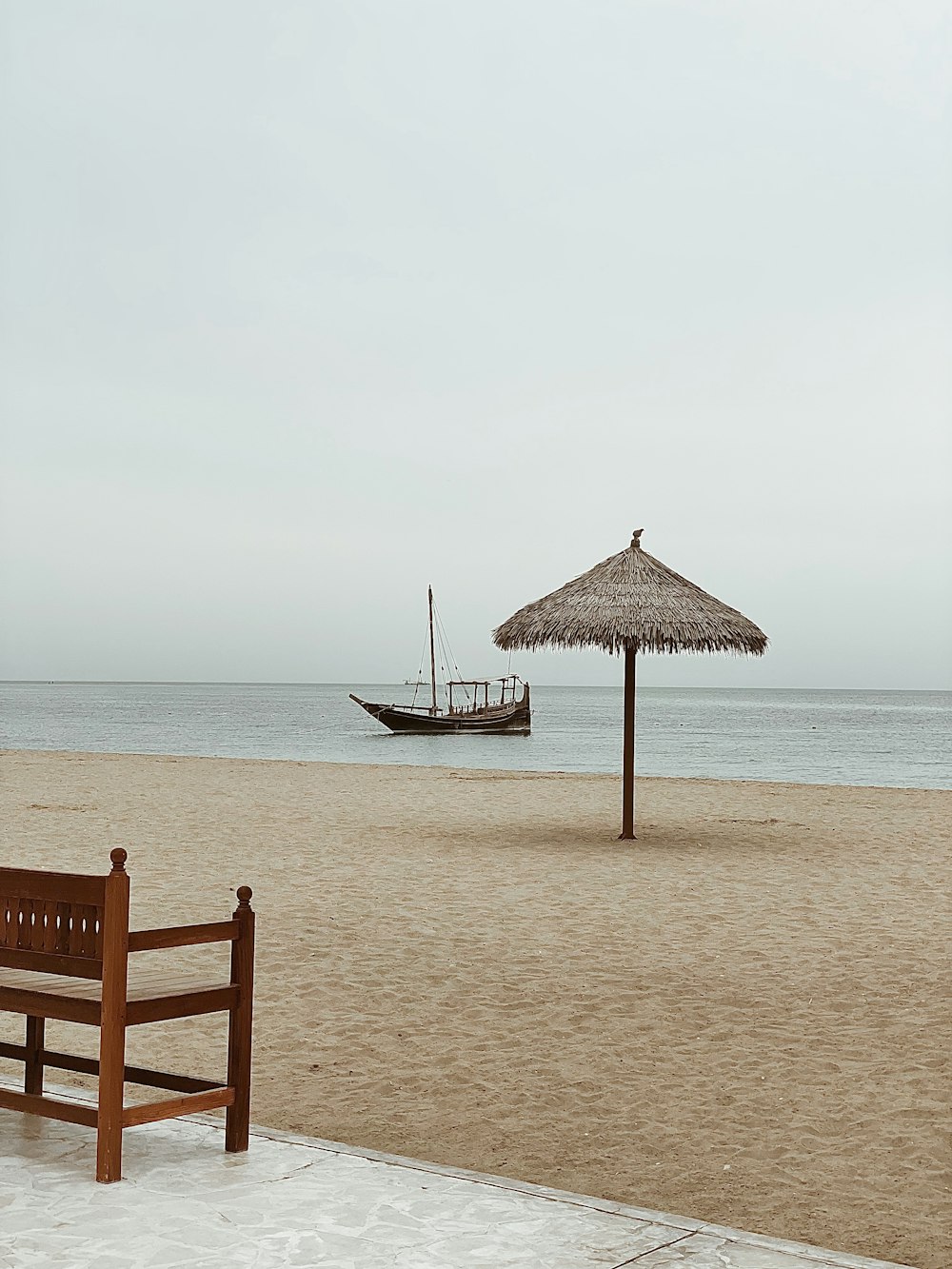 um banco de madeira sentado em cima de uma praia de areia