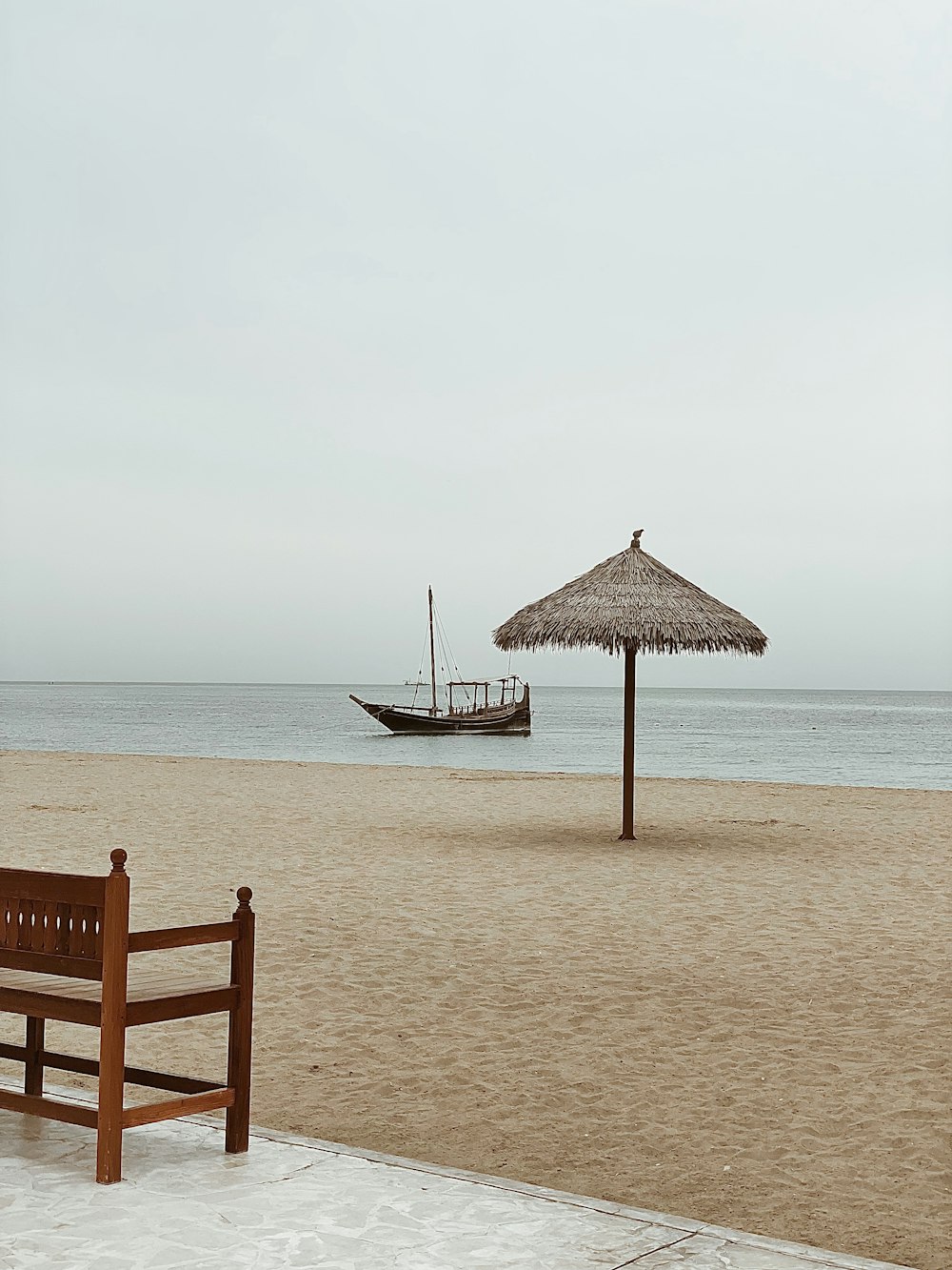 a wooden bench sitting on top of a sandy beach