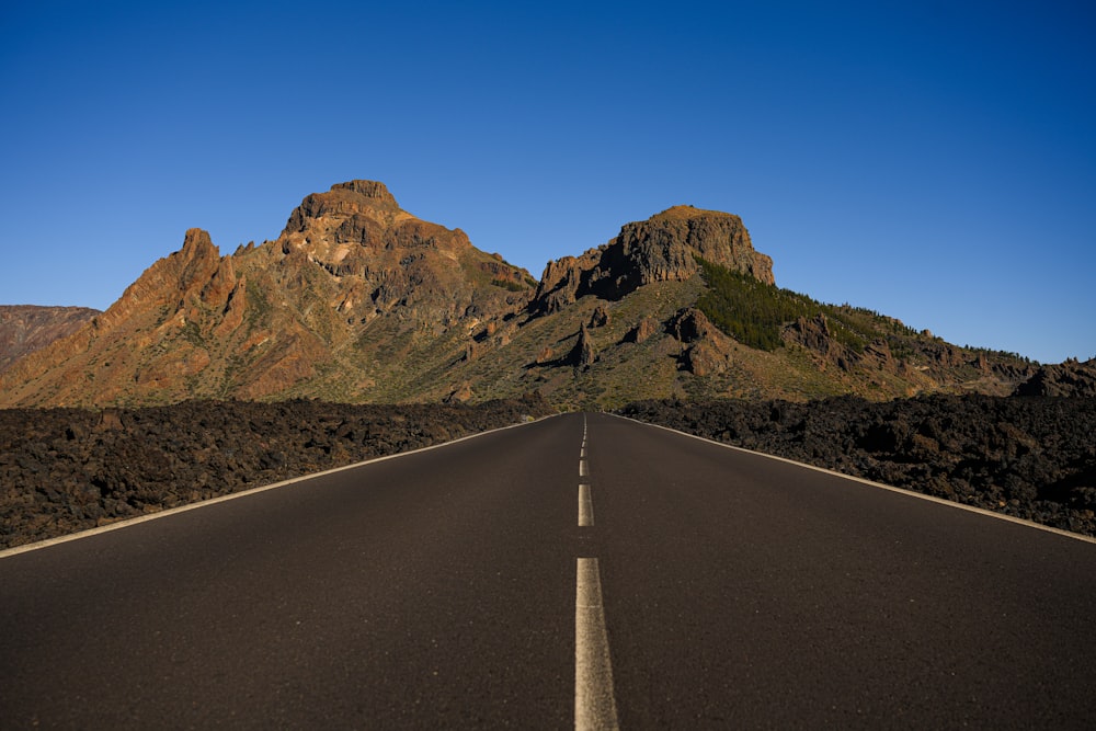 an empty road with mountains in the background