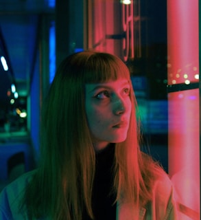 Silhouette of a woman with flowing hair against a glowing neon cityscape background.