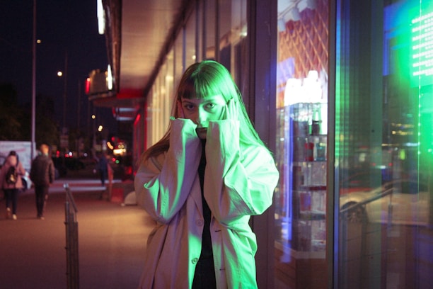 A shadowy figure in a trench coat stands against a neon-lit cityscape, blending comic noir with digital art vibes.