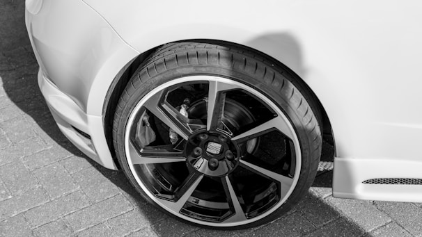 Close-up of a mechanic influencer showcasing new tires on a sports car.