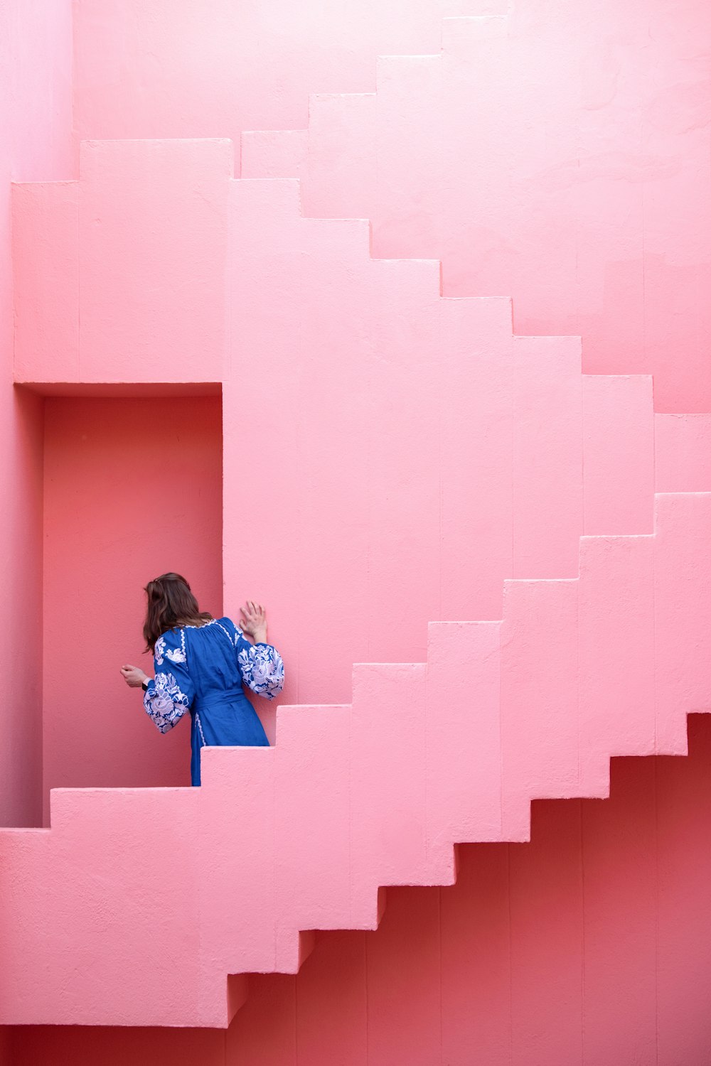 a woman in a blue dress standing on a pink staircase
