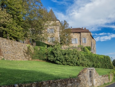 a stone house with a green lawn and a stone wall
