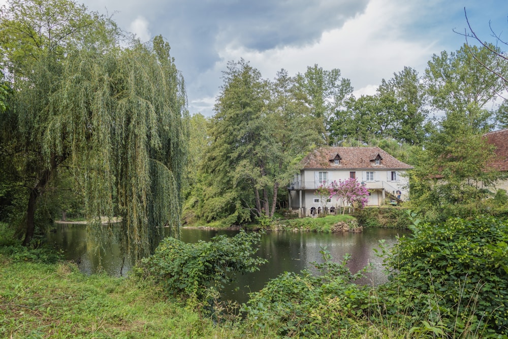 uma casa sentada ao lado de um lago cercado por árvores